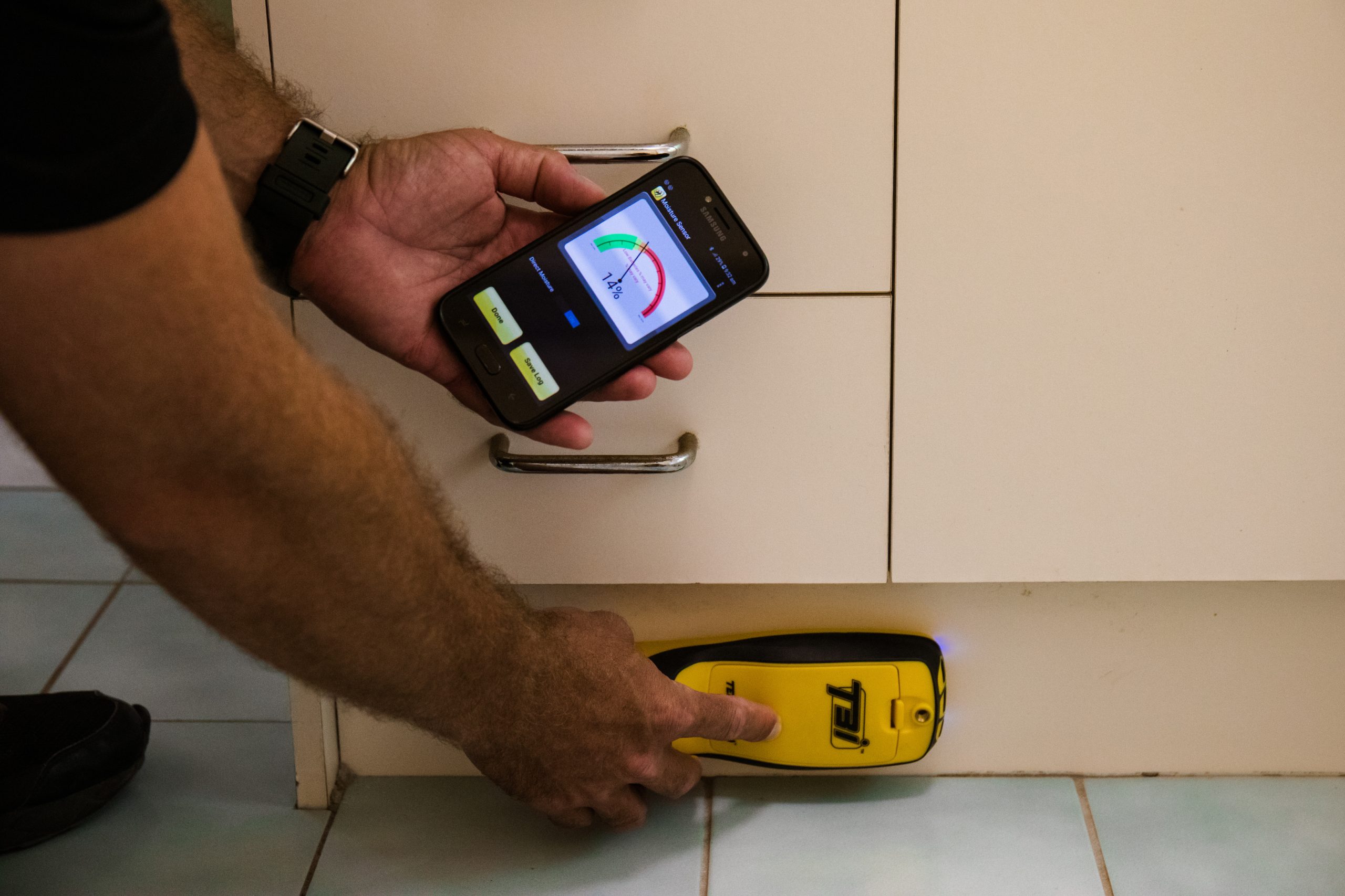 Qualified building inspector using device to measure moisture levels and identify potential termite risk areas